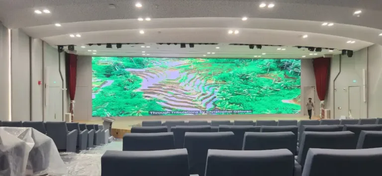 A large auditorium featuring a big digital display screen, designed for events and presentations.