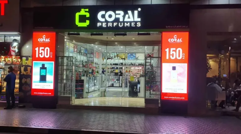 The front of a shop displaying Dubai LED displays that says "coral" welcoming visitors.