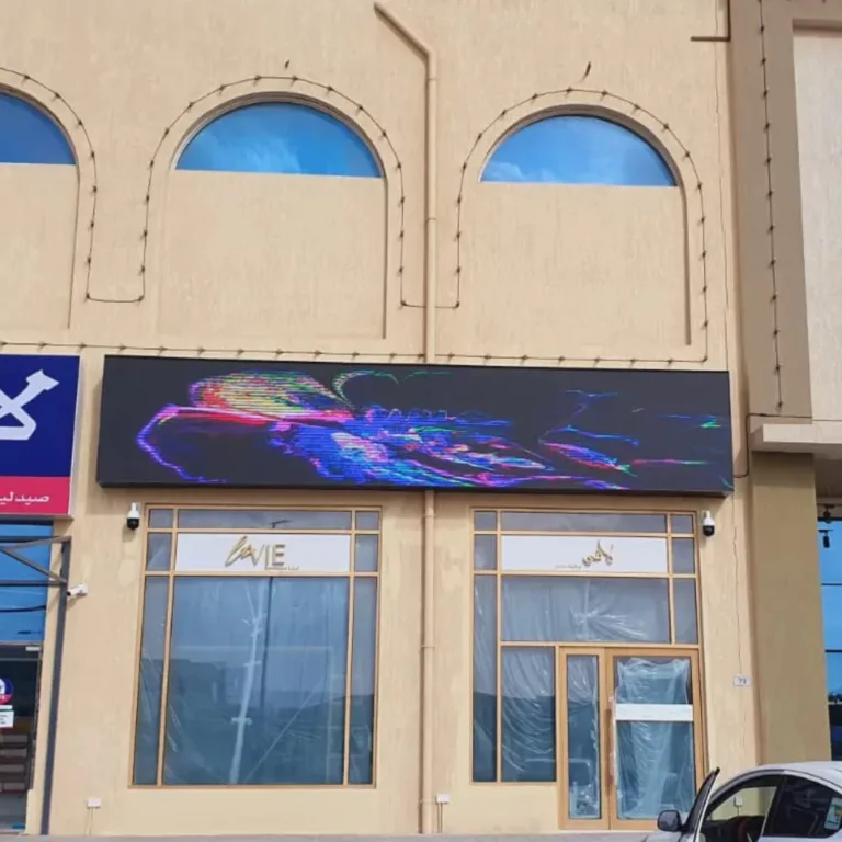 A large building with an outdoor LED screen on storefront, displaying bright visuals and ads.