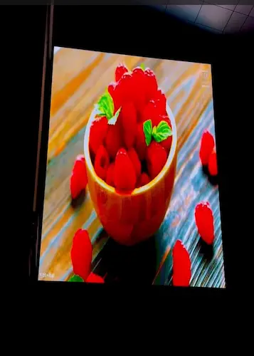 An outdoor LED video display a vibrant bowl filled with fresh, red raspberries.