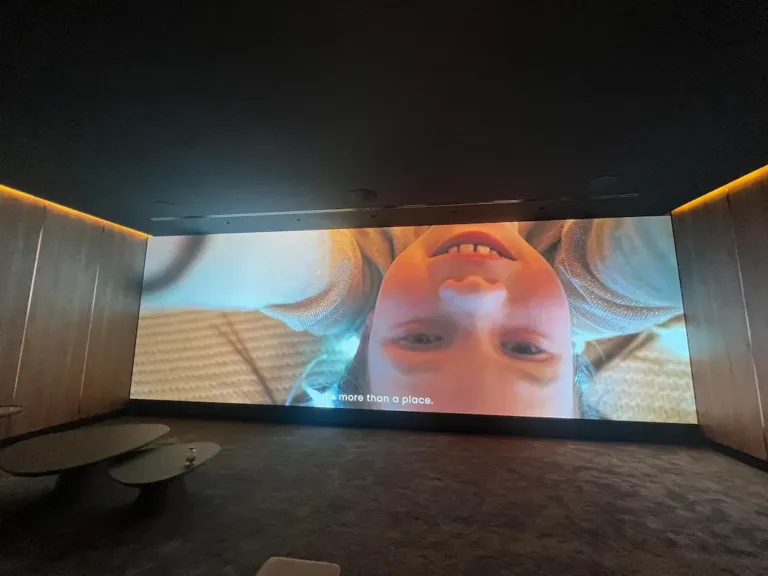 A large indoor LED screen displays a child's smiling face, filling the room with warmth and joy.