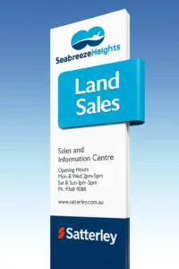 A land sales advertisement is featured on a totem signs or 3D signs positioned in front of a building.