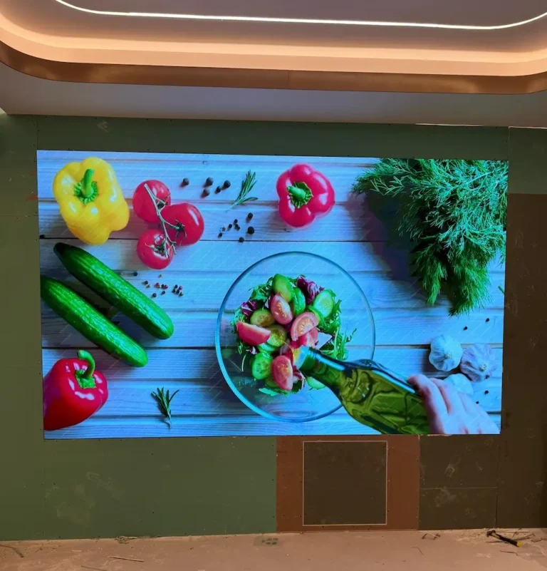 An indoor LED screen showcases colorful fruits and vegetables.