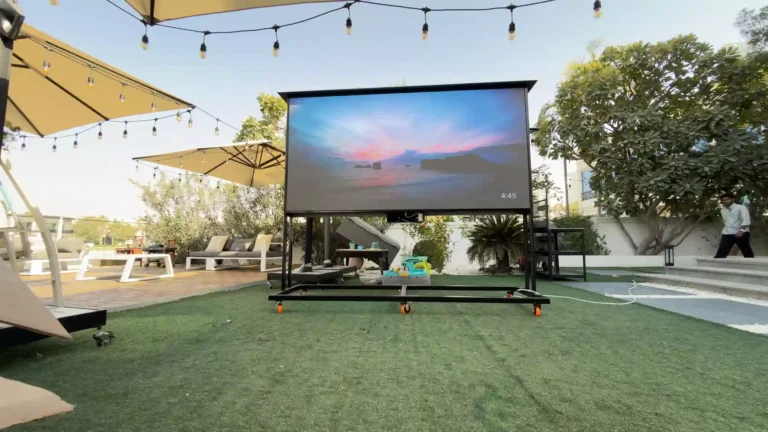 Outdoor LED screen on a lawn displaying a vibrant beach scene.