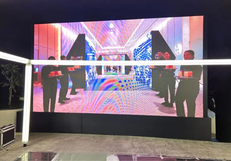 An outdoor LED screen display content as a crowd of people stands in front.