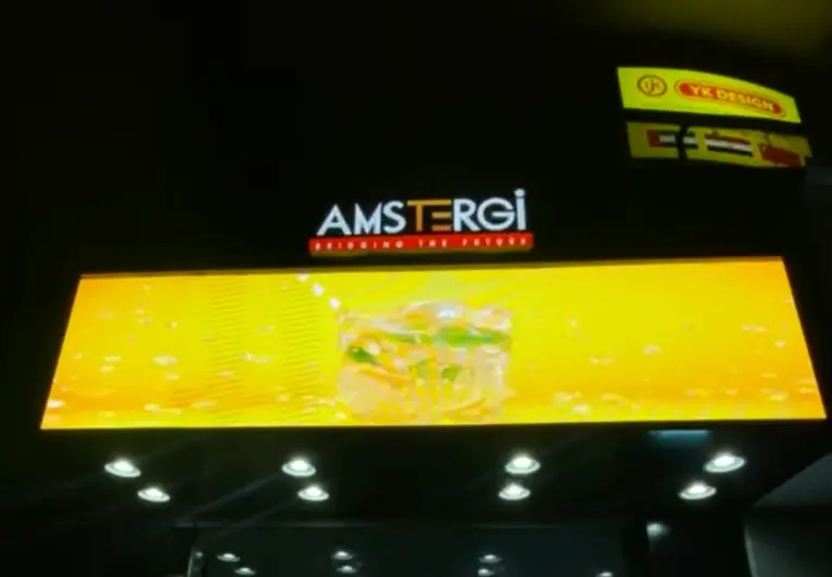 Shop name 'Amstegi' displayed on a LED display screen, visible in the night.