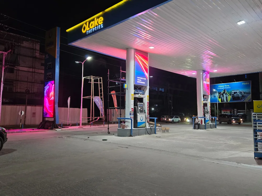 Gas station at night with outdoor LED display screens illuminating the scene.