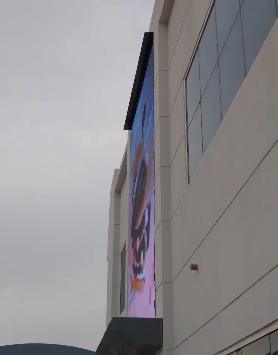 A building with a large digital signage screen, displaying dynamic visuals on its side.