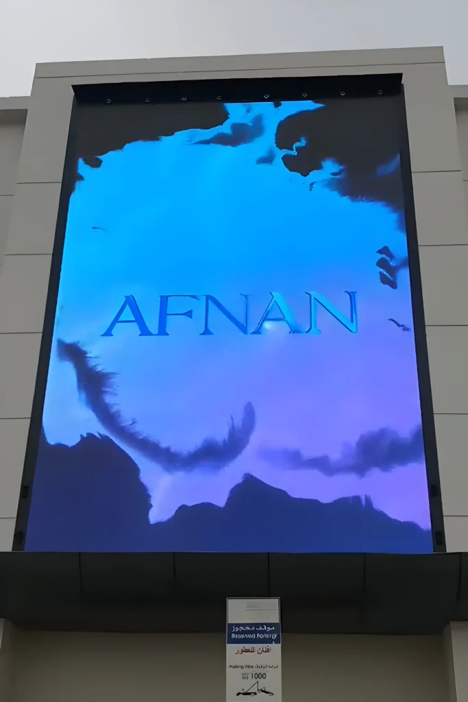Large vertical outdoor LED wall screen on a building facade displaying the AFNAN logo.