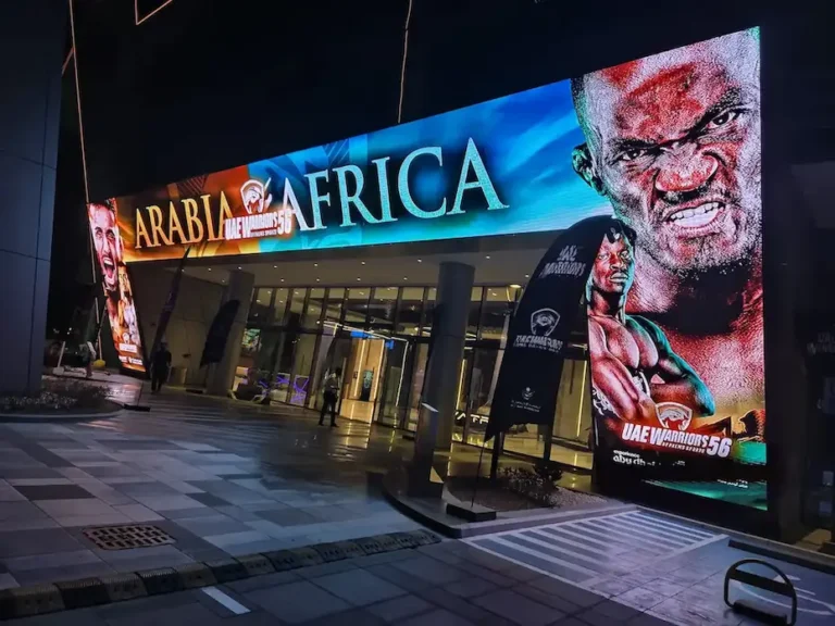 Large outdoor LED screen at a building entrance displaying advertisement.
