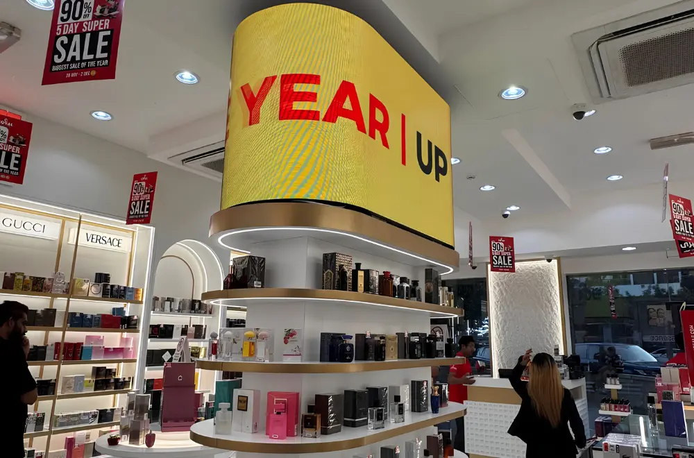 Curved flexible LED screen above a perfume display shelf in a retail store