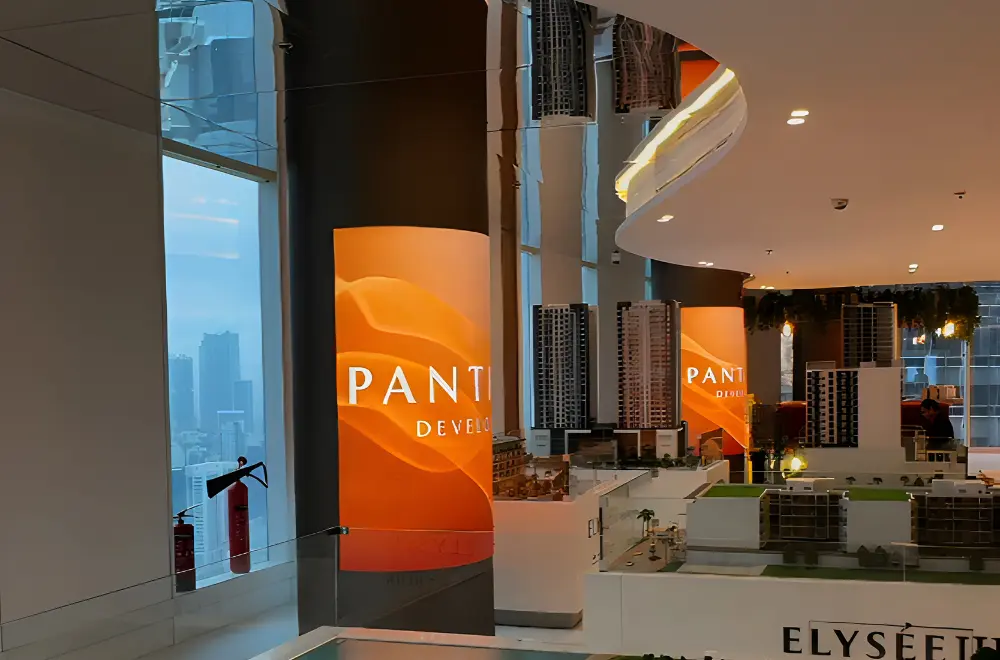 Flexible LED screens wrapped around columns in a property showroom showing orange branded visuals