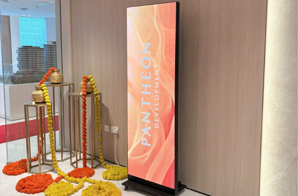 Indoor LED poster display on a wheeled stand in a real estate showroom