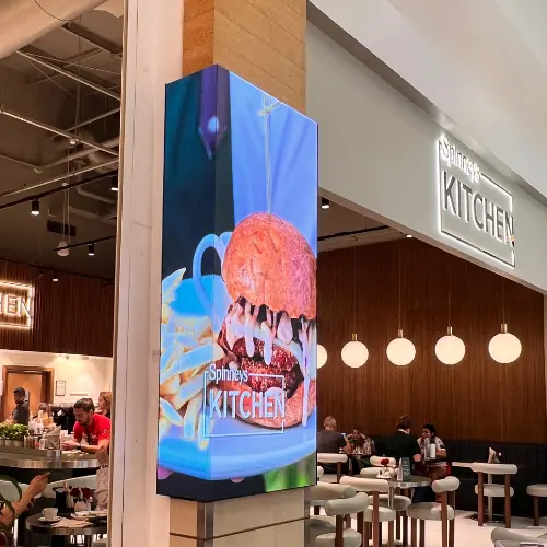 corner-wrapped indoor LED screen display at a restaurant entrance inside a mall