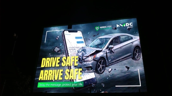 Outdoor LED advertising screen at night displaying a bright road safety campaign visual