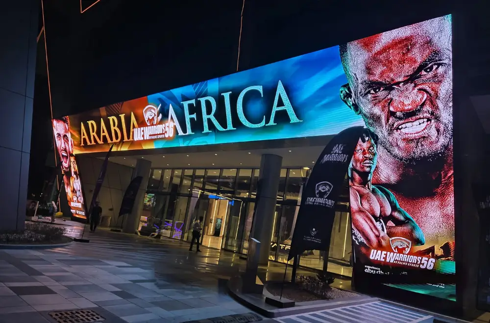 Large curved outdoor LED screen, showing a UAE Warriors 56 event promotion