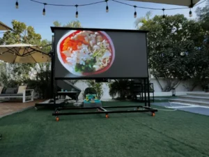 Outdoor portable LED screen display on grass, showing an image of a food bowl.