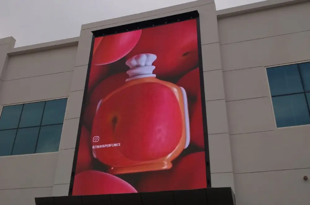 vertical outdoor LED wall screen mounted on a building facade, showing a perfume ad
